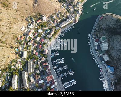 Vue panoramique aérienne du paysage de Balaklava avec des bateaux et la mer dans la baie de la marina au coucher du soleil. Attraction touristique de Crimée Sébastopol. Vue de dessus de drone Banque D'Images