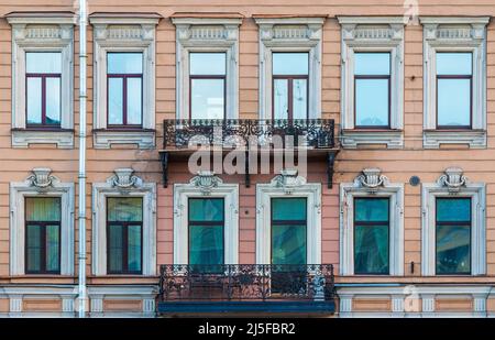 Deux balcons et de nombreuses fenêtres dans une rangée sur la façade de l'immeuble urbain historique d'appartements vue de face, Saint-Pétersbourg, Russie Banque D'Images