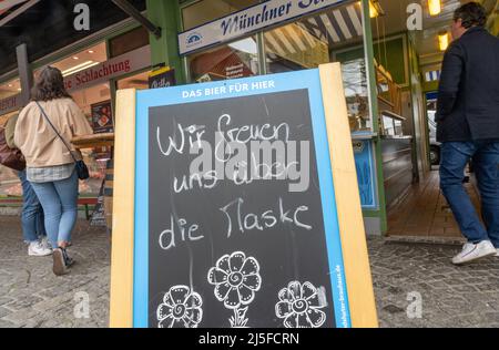 Munich, Allemagne. 23rd avril 2022. Un panneau indiquant « nous sommes heureux du masque » se trouve devant un magasin sur le Viktualienmarkt. Depuis le début du mois d'avril, il n'est plus nécessaire de porter des masques dans la plupart des régions d'Allemagne, du moins lors des achats. Mais la prudence prévaut chez de nombreux clients. Credit: Peter Kneffel/dpa/Alay Live News Banque D'Images