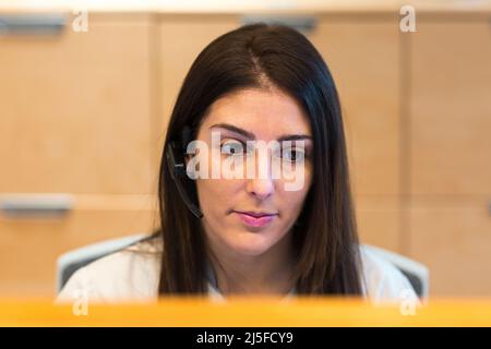 Un réceptionniste portant un casque tout en travaillant à la réception d'un centre de santé ou de beauté. Banque D'Images