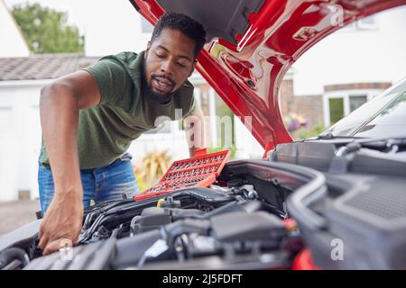 Homme travaillant sous le capot d'une voiture fixant le moteur à l'aide d'une clé Banque D'Images