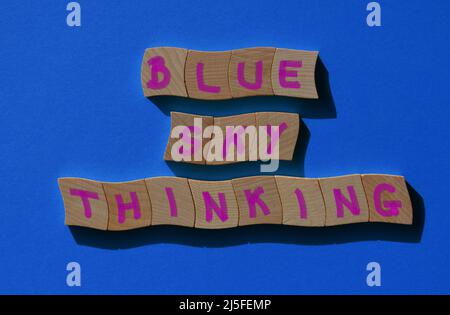 Blue Sky Thinking, phrase en lettres de l'alphabet de bois isolées sur fond bleu Banque D'Images