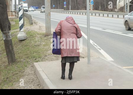 Homme à l'arrêt de bus en Russie. La fille attend le transport. Un homme au bord de la route. Banque D'Images