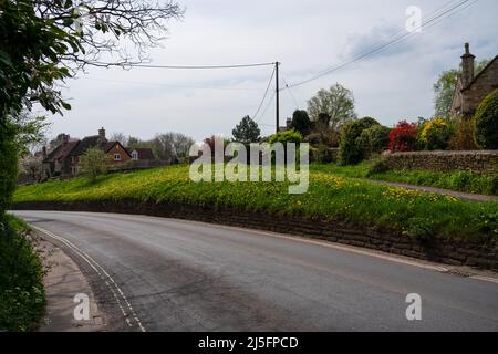 une route de village sur un virage et au sommet d'une colline, herbe et buissons de jardin arrière-plan Banque D'Images