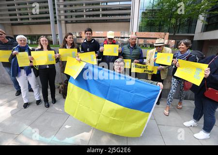 Le porte-drapeau Myron Tytko et d'autres supporters portent des bannières alors qu'ils se joignent à un groupe d'hôtes, de sponsors et de partisans des réfugiés ukrainiens, tiennent une Vigile pour les visas à l'extérieur du Home Office à Londres. Date de la photo: Samedi 23 avril 2022. Banque D'Images