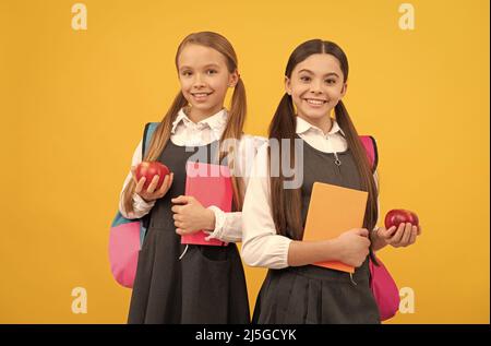 Développer les connaissances sur une alimentation saine. Les enfants tiennent des livres et des pommes. Alimentation nutritive à l'école Banque D'Images