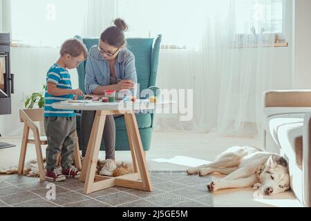 Maman et enfant peignent ensemble à la maison avec le chien Banque D'Images