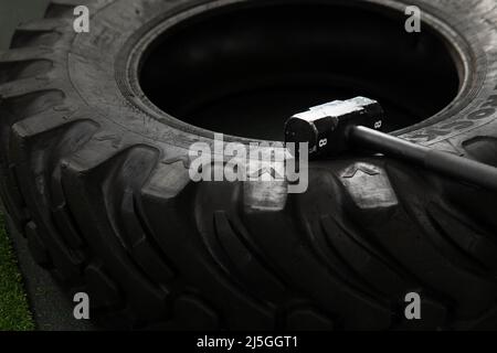 Black Wheel pneu sledgehammer crossfit entraînement athlète musculation exercice, à partir de la croix énorme dans la forme et sport musclé, sportswear flipping. Homme grand Banque D'Images