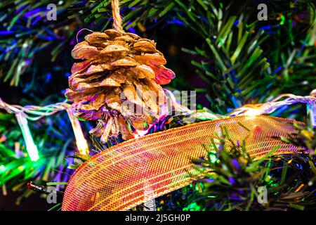 La pendaison de Noël décorations sur sapin. Arbre de Noël décoré. Branches de sapin avec cône de pin entouré de lumières et de guirlandes. Banque D'Images