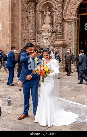 Un jeune couple péruvien quitte la cathédrale après s'être marié, la Plaza de Armas, Puno, Pérou. Banque D'Images