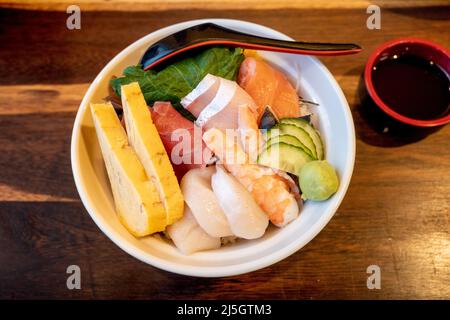 Vue de dessus de Sashimi Don, Danburi ou bol à riz japonais avec différentes tranches de poisson frais, crevettes, calmar et œuf de tamago, sur le comptoir en bois sombre. Banque D'Images
