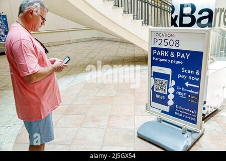 Miami Florida Coral Gables Shops at Merrick Park centre commercial extérieur haut de gamme parking garage scan de l'enseigne payer maintenant QR code hispanique homme smartpho Banque D'Images