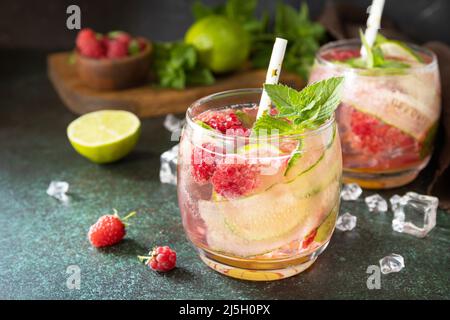 Boissons non alcoolisées, boissons saines, eau amincissante. Des boissons détox rafraîchissantes à base de framboises biologiques, de concombres, de chaux et de feuilles de menthe sur une table en pierre Banque D'Images