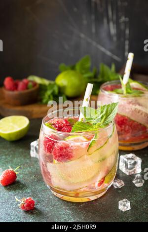 Boissons non alcoolisées, boissons saines, eau amincissante. Des boissons détox rafraîchissantes à base de framboises biologiques, de concombres, de chaux et de feuilles de menthe sur une table en pierre Banque D'Images