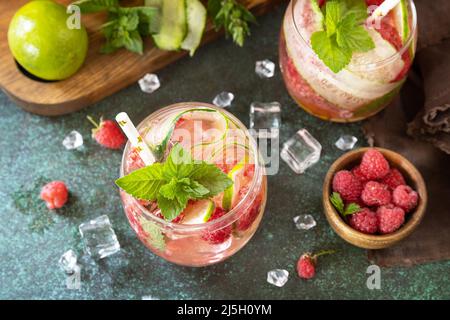 Boissons non alcoolisées, boissons saines, eau amincissante. Des boissons détox rafraîchissantes à base de framboises biologiques, de concombres, de chaux et de feuilles de menthe sur une table en pierre Banque D'Images