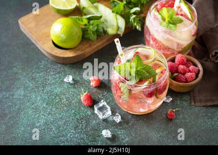 Boissons non alcoolisées, boissons saines, eau amincissante. Des boissons détox rafraîchissantes à base de framboises biologiques, de concombres, de chaux et de feuilles de menthe sur une table en pierre Banque D'Images