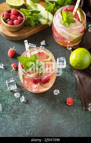 Boissons non alcoolisées, boissons saines, eau amincissante. Des boissons détox rafraîchissantes à base de framboises biologiques, de concombres, de chaux et de feuilles de menthe sur une table en pierre Banque D'Images