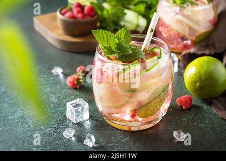 Boissons non alcoolisées, boissons saines, eau amincissante. Des boissons détox rafraîchissantes à base de framboises biologiques, de concombres, de chaux et de feuilles de menthe sur une table en pierre Banque D'Images