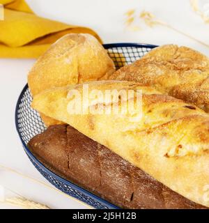 Composition alimentaire écologique avec trois pains frais dans le panier bleu sur fond blanc avec serviette. Maison naturelle différente sorte de Banque D'Images