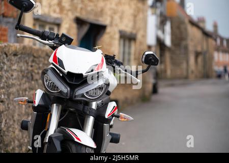 White triomphe Street triple S moto garée dans un village de 18th siècle rue Lacock Wiltshire Banque D'Images