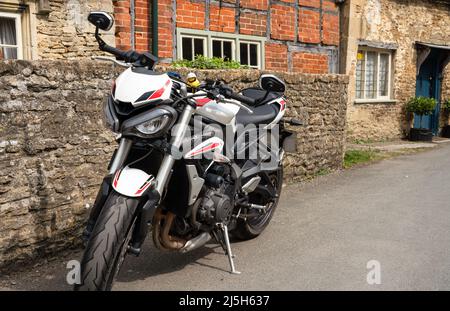 White triomphe Street triple S moto garée dans un village de 18th siècle rue Lacock Wiltshire Banque D'Images