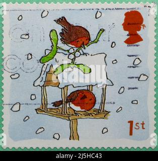 Photo d'un timbre-poste britannique de Noël avec une illustration de deux oiseaux rouges-rouges sur une table d'oiseaux enneigée 2001 Banque D'Images