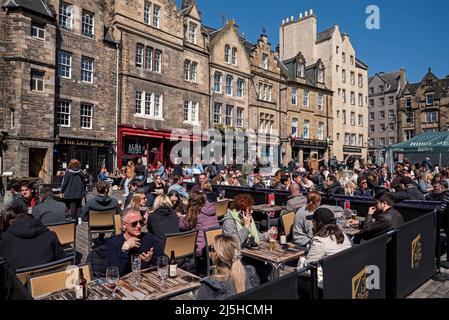 Touristes et locaux se détendant dehors et appréciant le soleil de printemps dans le Grassmarket, Edimbourg, Ecosse, Royaume-Uni. Avril 2022. Banque D'Images