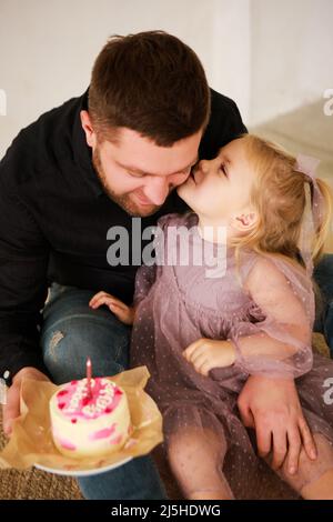 Le père et le dauther célèbrent l'anniversaire de leur petite fille.Fête d'anniversaire en robes avec gâteau. Banque D'Images