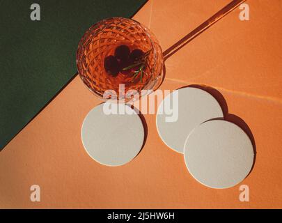 Dessous-de-verre en papier blanc de style boho avec un verre à vin et des feuilles de palmier séchées à côté, à utiliser comme maquette Banque D'Images