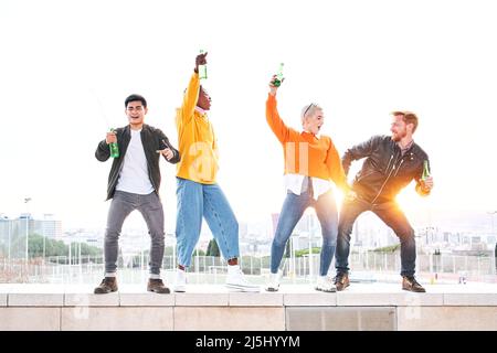 Groupe de personnes diverses dansant l'amusement à l'extérieur de boire de la bière et de s'amuser. Des amis heureux célébrant ensemble le succès. Bonheur et Banque D'Images