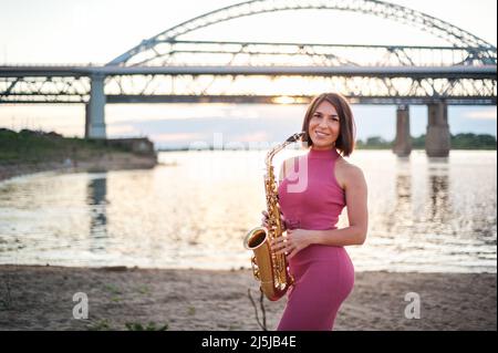 Femme jouant le saxophone au coucher du soleil Banque D'Images