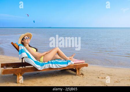 jeune femme en chapeau de paille et lunettes de soleil se détendant sur un transat Banque D'Images