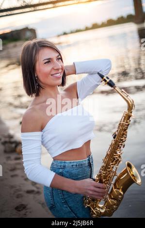Femme jouant le saxophone au coucher du soleil Banque D'Images