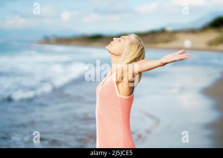 Belle femme mûre ouvrant ses bras sur une belle plage, appréciant son temps libre Banque D'Images