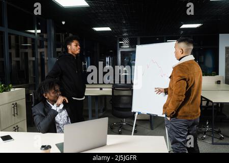 Les investisseurs multiethniques discutent du graphique des crypto-monnaies et du bitcoin. Les hommes d'affaires d'Afrique noire et d'Asie discutent de la place financière économique Banque D'Images