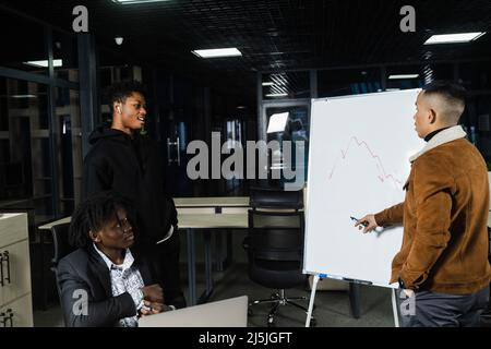 Les investisseurs multiethniques discutent du graphique des crypto-monnaies et du bitcoin. Les hommes d'affaires d'Afrique noire et d'Asie discutent de la place financière économique Banque D'Images