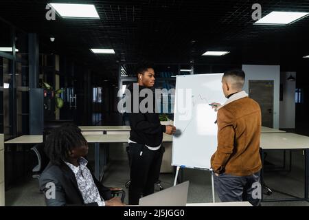Les crypto-monnaies et les bitcoins sont des discussions graphiques par des investisseurs multiethniques. Les hommes d'affaires d'Afrique noire et d'Asie discutent de la place financière économique Banque D'Images