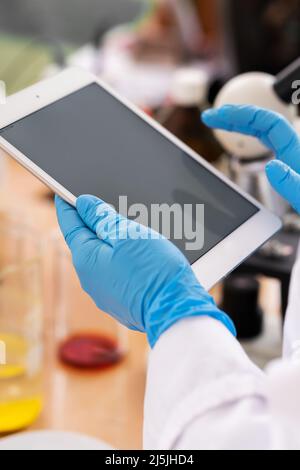 Gros plan des mains du scientifique dans les gants en latex avec un PC tablette Banque D'Images