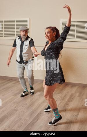 Couple adulte senior dansant le saut de lindy dans une salle de bal Banque D'Images