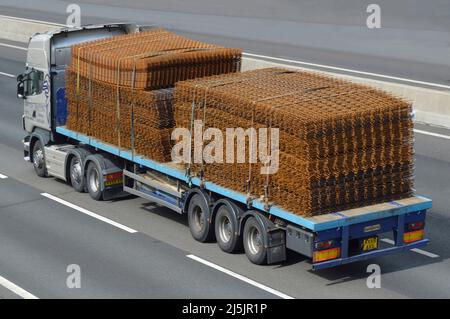 Vue latérale et arrière de l'antenne camion hgv et remorque à plateau chargée rouille sur construction de bâtiment en acier renforcement du maillage conduite sur route autoroutière britannique Banque D'Images