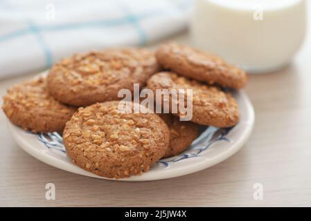 Gros plan des biscuits aux flocons d'avoine avec chapelure d'arachide et verre de lait sur une table en bois Banque D'Images