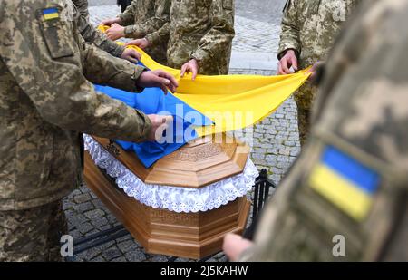 Des militaires couvrent le cercueil d'un militaire ukrainien tué lors de l'invasion de l'Ukraine par la Russie avec un drapeau ukrainien lors de ses funérailles Banque D'Images