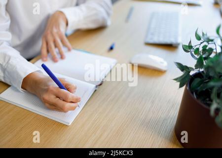Gros plan de la main d'une femme avec un stylo écrit dans un bloc-notes Banque D'Images