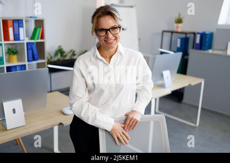 Femme d'affaires mûre souriante au bureau Banque D'Images
