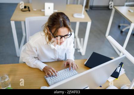 La femme d'affaires d'âge moyen se concentre sur le travail à un ordinateur Banque D'Images