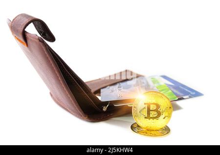 Pièce en bitcoin crypto-monnaie à côté du portefeuille marron. Les cartes de paiement de différentes banques sont visibles sur le portefeuille. Accumulation de Bitcoin, commerce, vente Banque D'Images