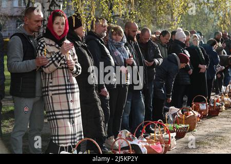 BUCHA, UKRAINE - AVRIL 24, 2022 - les gens attendent que leurs paniers soient consacrés avec de l'eau sainte à l'extérieur de l'Église de Saint Andrew le premier appelé Apôtre lors de la célébration orthodoxe de Pâques à Bucha qui se remet des crimes de guerre commis par les troupes russes après sa libération des envahisseurs russes, région de Kiev, dans le nord de l'Ukraine. Credit: UKRINFORM/Alamy Live News Banque D'Images