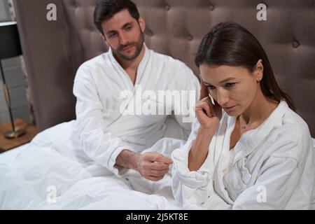 Homme qui fait amende avec sa femme dans le lit de l'hôtel Banque D'Images