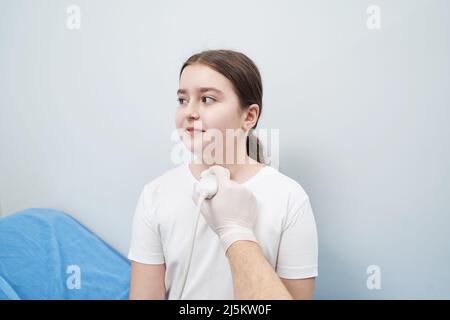 Jeune fille caucasienne subissant une échographie de la glande thyroïde à la clinique Banque D'Images