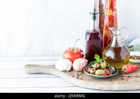 Vinaigre d'huile et de vin rouge en bouteilles de verre avec olives et grains de poivre. Banque D'Images